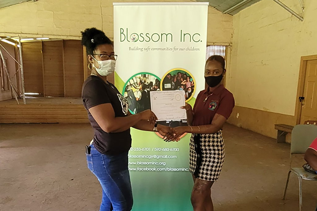 A participant of the workshop receives a certificate of completion from Education Awareness Officer at Blossom Inc., Joses Solomon